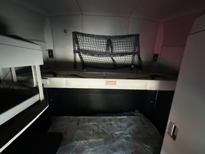 Kenworth T680 sleeper cab interior cargo area with bunk bed and net, rear storage area visible.