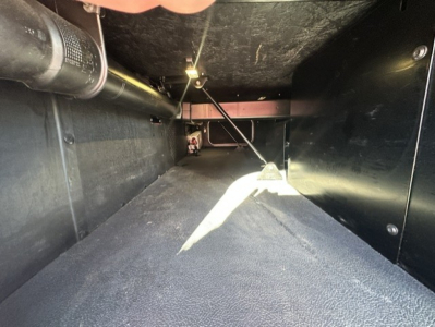 Kenworth T680 truck interior storage compartment with black panels and a central support, showing a narrow under-seat area.