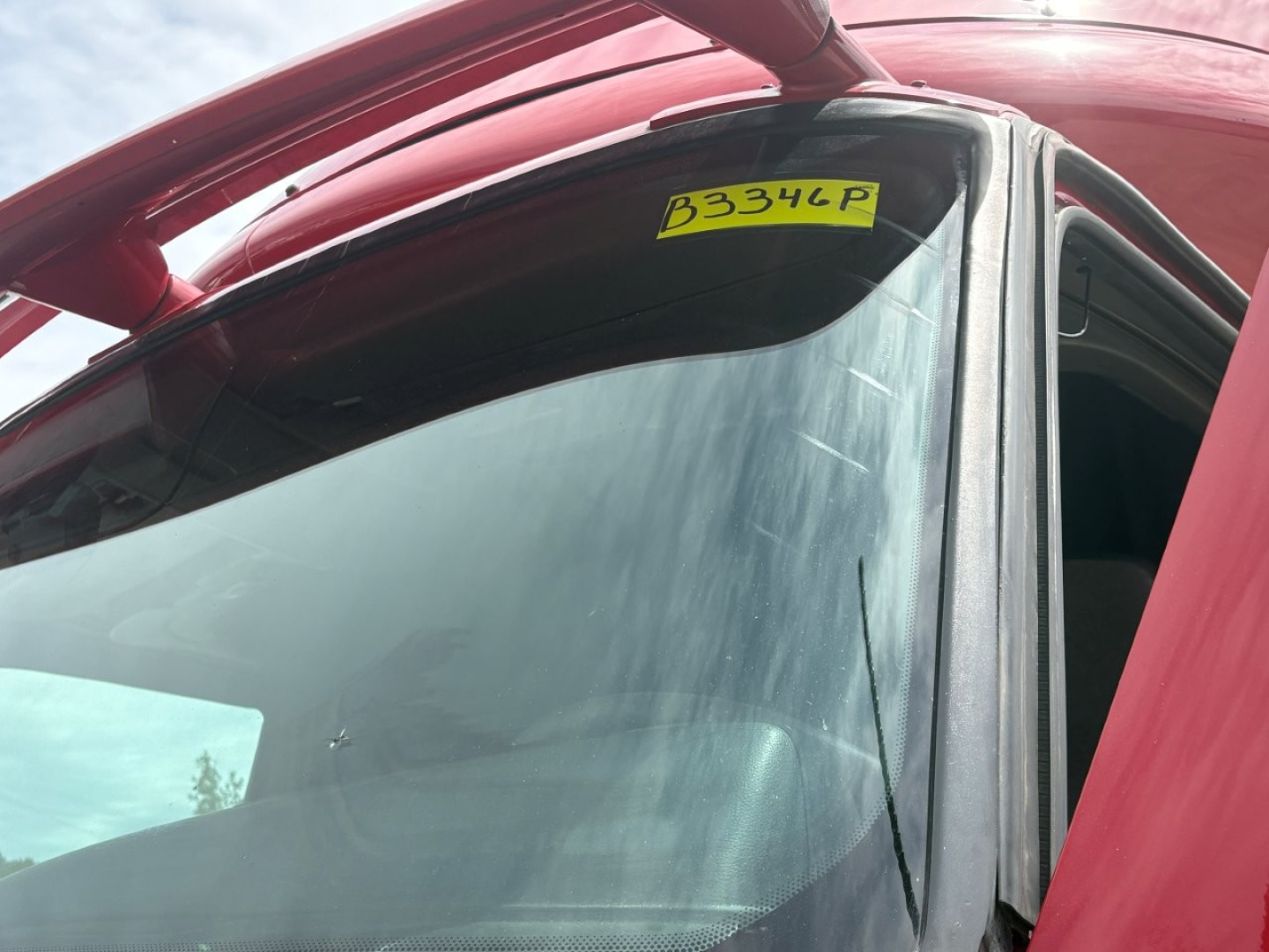 Tractor truck cab window with a yellow stock sticker reading B334P on the windshield.