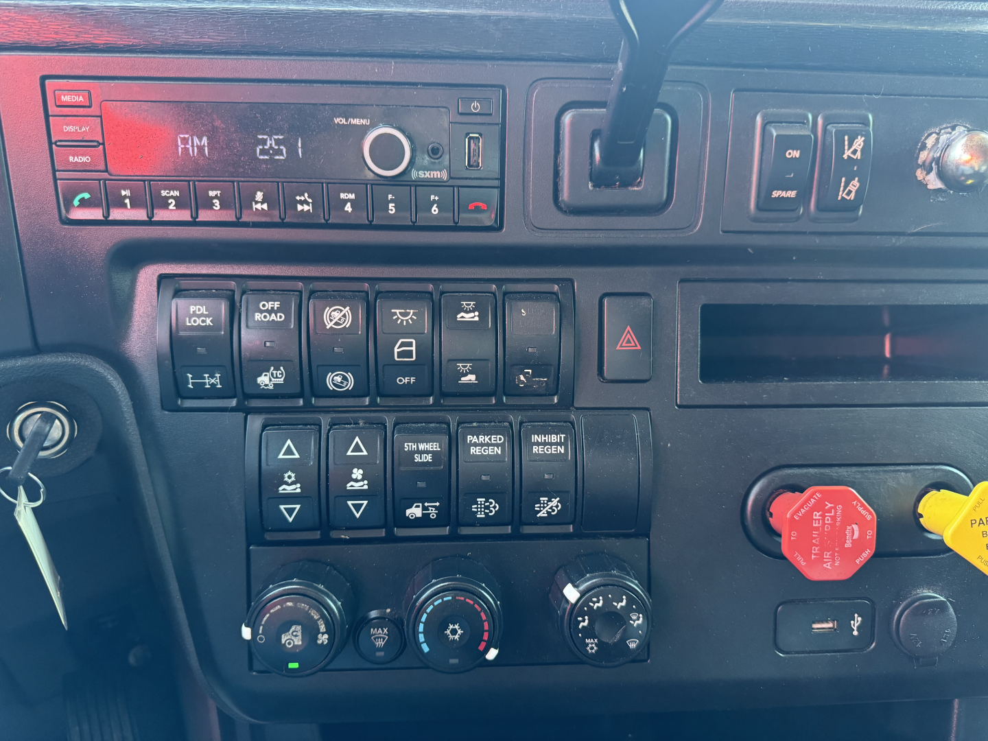 Dashboard of a 2022 International LT truck showing radio display, control switches, climate knobs, and a red engine start/stop style knob; various labels visible on buttons and gauges.