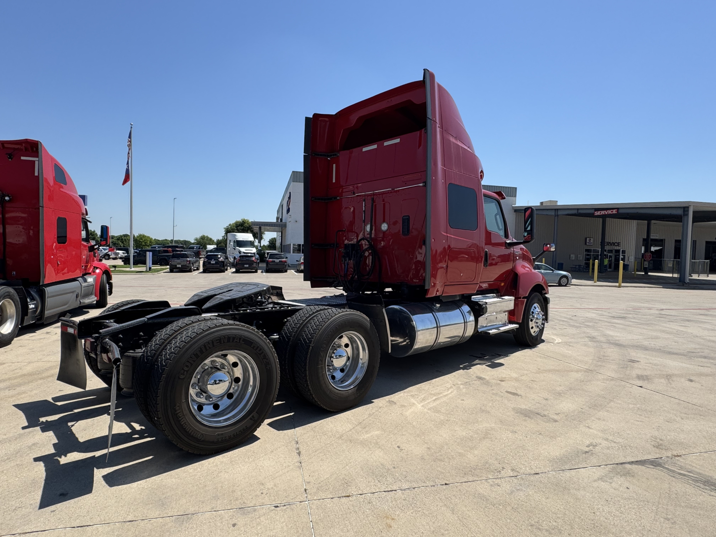International LT tractor in red, side view showing chassis with dual rear axles and fuel tanks, sleeper cab, no trailer attached.