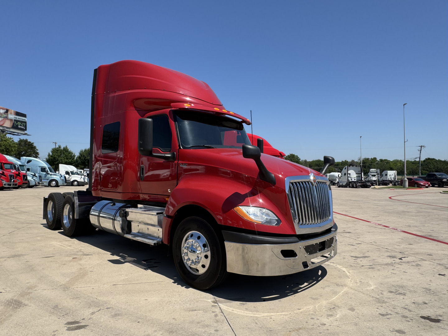 International LT truck cab in red, front three-quarter view with sleeper, chrome bumper and dual rear axles.