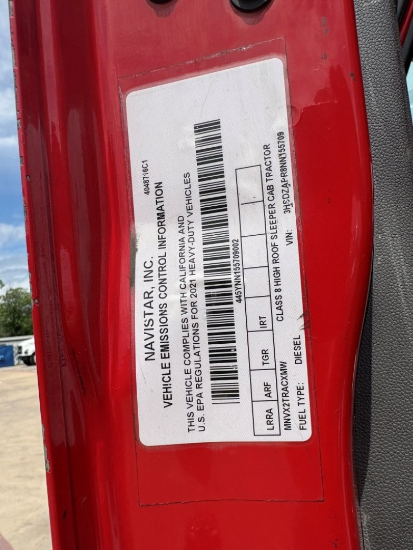 Label on red truck door shows vehicle information including VIN and OEM labels, with a barcode and various vehicle details in small print.