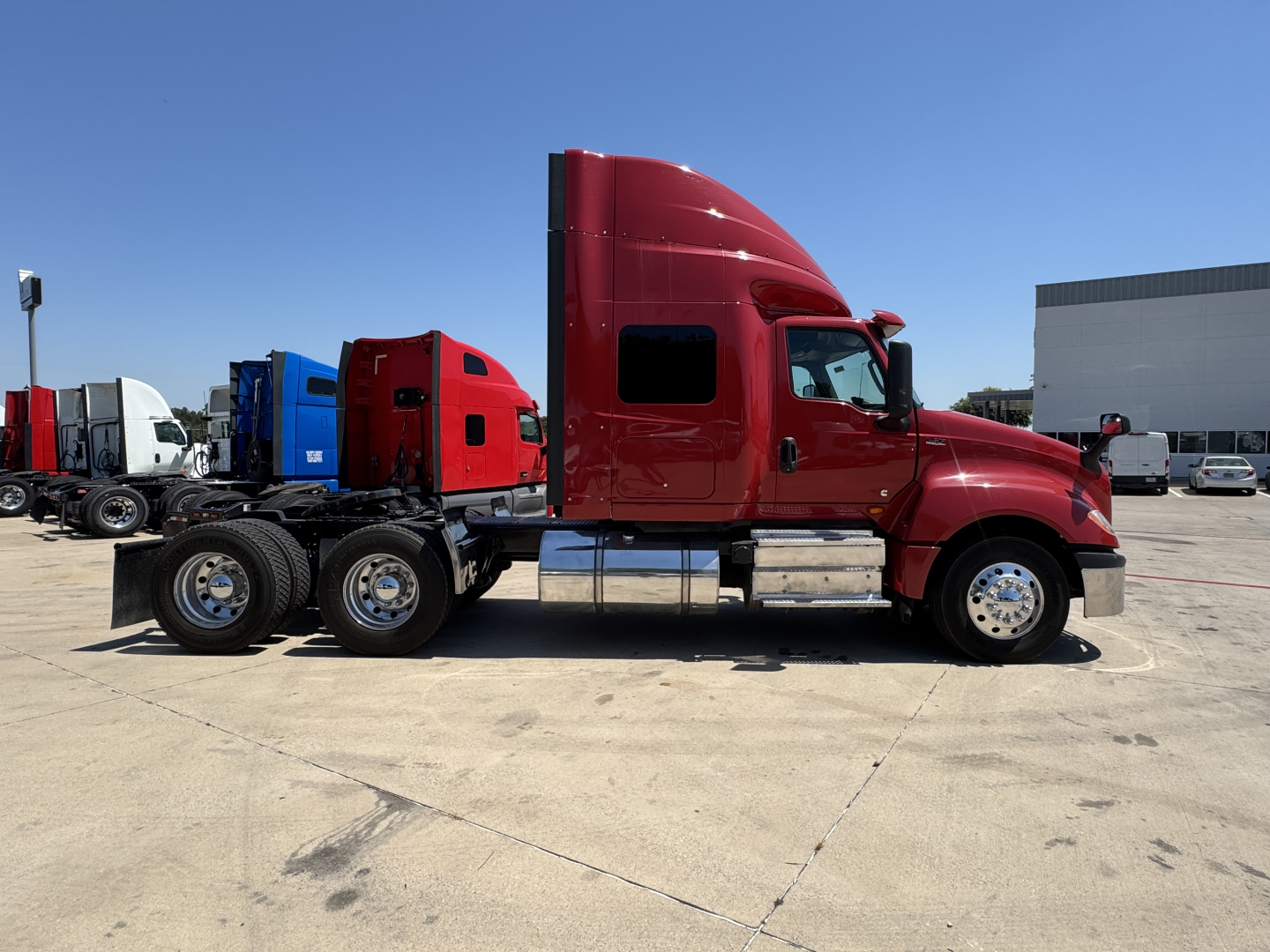 Side profile of a red 2022 International LT conventional sleeper truck showing cab, dual rear axles, and chrome fuel tanks.