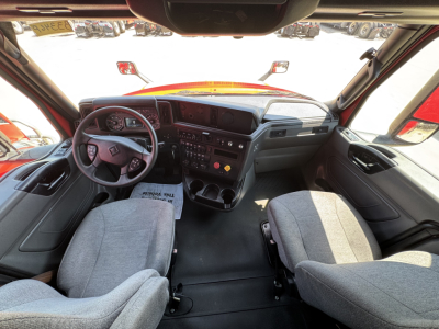 Interior of a 2022 International LT truck cab showing steering wheel, dashboard with gauges, central control panel, and two grey fabric seats.