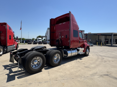 International LT tractor in red, side view showing chassis with dual rear axles and fuel tanks, sleeper cab, no trailer attached.