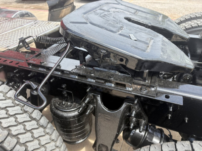 Rear view of a semi truck chassis showing the fifth-wheel coupling, air tanks, and suspension components under a used International LT truck.