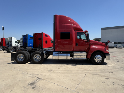 Side profile of a red 2022 International LT conventional sleeper truck showing cab, dual rear axles, and chrome fuel tanks.