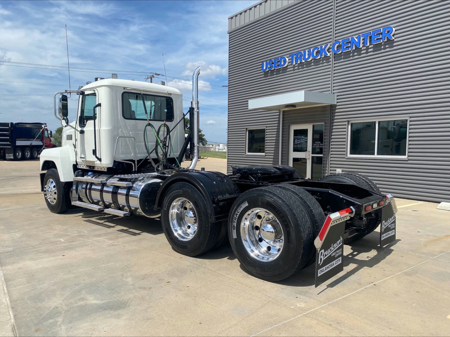 2021 Mack PI64T tractor cab from rear-left side showing dual rear axles and chassis in front of used truck center.