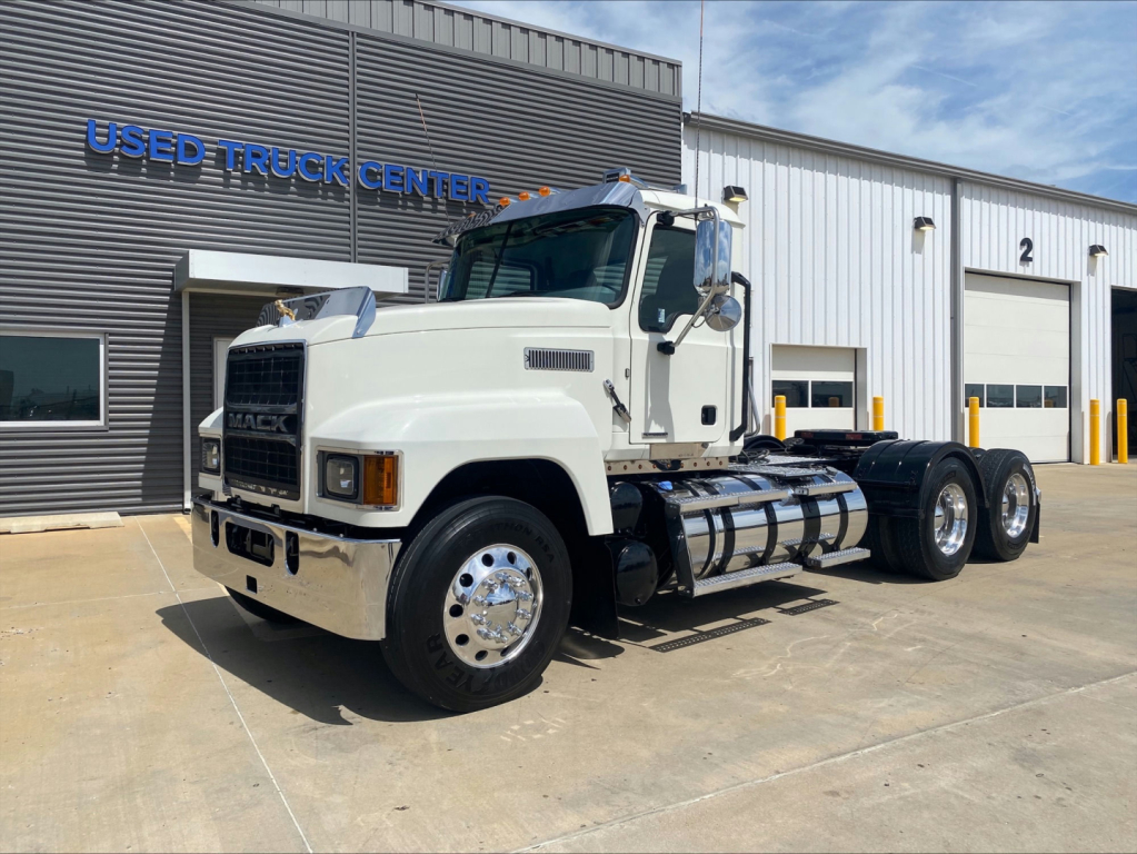 Truck front/side view of a white 2021 Mack PI64T conventional daycab with dual rear axles, parked outside Used Truck Center.