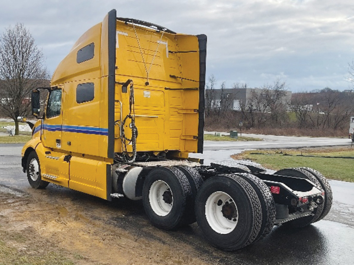 Volvo VNL 760 truck tractor side view showing sleeper cab in yellow with blue stripe and rear tandem wheels