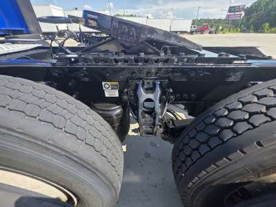Kenworth truck chassis showing fifth wheel and dual rear tires with linkage and mounting components.