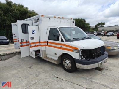 Ambulance vehicle side view showing empty front grille, white body with orange stripes, number 27 on door and rear, and compartment doors.