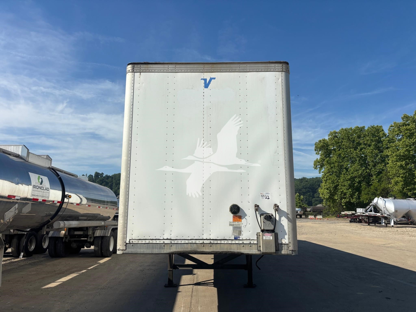 Vanguard VXP trailer rear view showing white silhouette graphic and blue 'V' logo on a white doors, with bumper and hitch area visible.