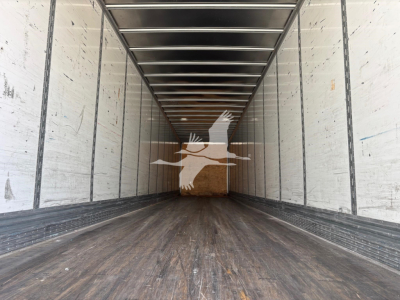 Trailer interior showing long empty cargo area with wooden floor, metal sidewalls, and ceiling beams.