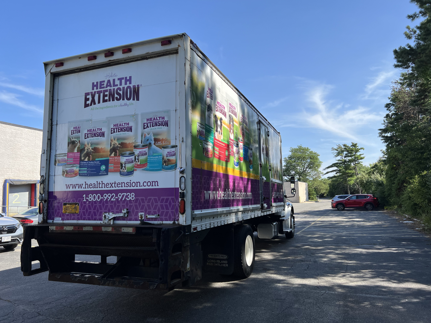 Truck with Health Extension wrap in a parking lot. Side displays Health Extension branding and contact info. CDL rear view shows box truck with purple graphics.