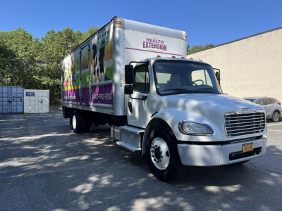 Freightliner M2 box truck side view showing Health Extension graphics and aluminum cab with chrome grille.