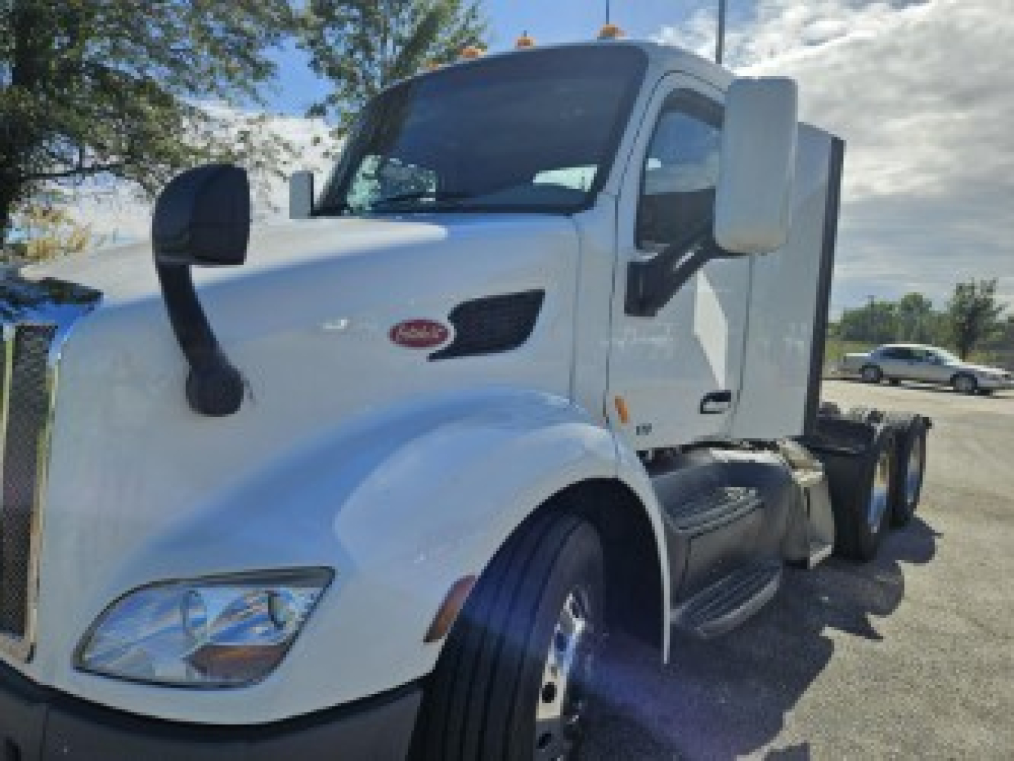 Peterbilt 579 truck cab in white, front left view, with dual mirrors and fuel/step side, heavy-duty tractor configuration.