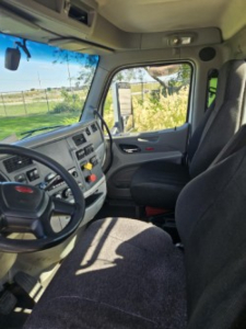 Peterbilt 579 truck cabin interior view showing steering wheel, dashboard, and front seats