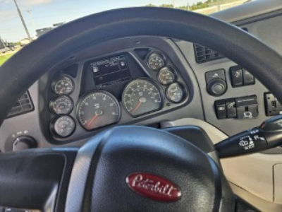 Peterbilt steering wheel with instrument cluster and controls in the dash view. Visible gauges and small digital display.