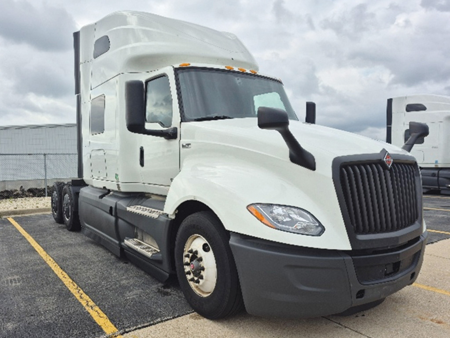 Truck cab exterior showing International LT625 with sleeper, white cab, long hood, dual rear axles, front grille and headlights visible.