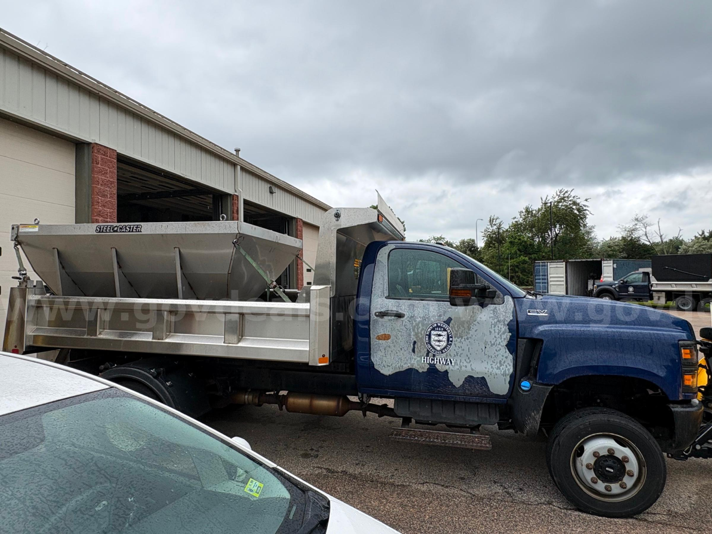 International CV515 dump truck in side view showing dump bed, cab with blue paint, and wheeled front. Visible text on door and truck body.