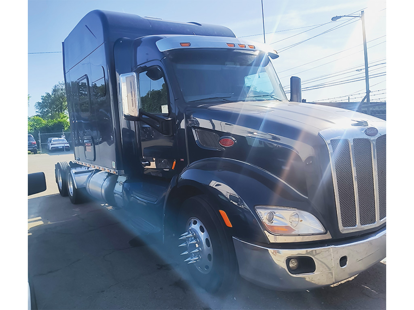 Peterbilt 579 UltraCab truck with black exterior, front grille, headlights, large chrome bumper. Side view shows sleeper cab, fuel tanks, and dual rear wheels.