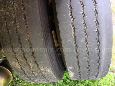 Two rear tires of a Freightliner 114SD truck showing worn tread and mud, with partial wheel well and chassis visible.