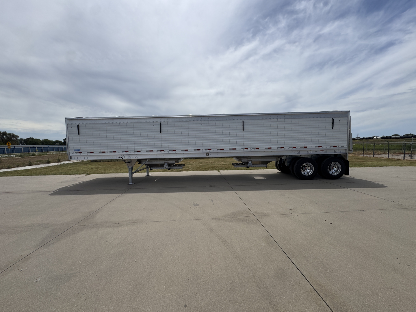 Aluminum grain hopper trailer side view showing corrugated 74" sidewalls and tandem axles.