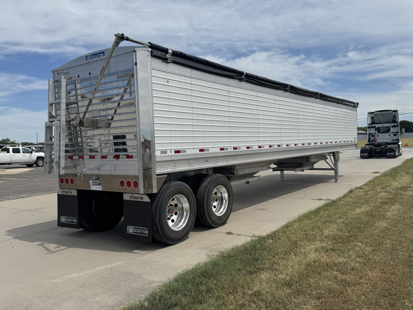 Trailer side view of a 2027 Stoughton 42' aluminum grain hopper with 74" corrugated sidewalls, dual rear axles, tarp cover, and rear gate.