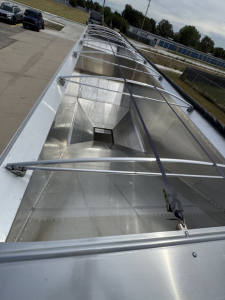 Aluminum grain hopper trailer roof view showing corrugated sidewalls and ladder framework along top edge.