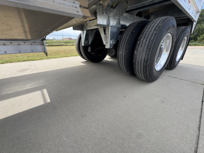 Stoughton 42' aluminum grain hopper trailer underside showing dual-axle wheels and corrugated sidewalls.