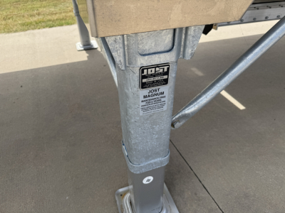 Trailer hitch leg with JO ST Magnum label and corrugated sidewall visible on a 42ft alum grain hopper trailer.