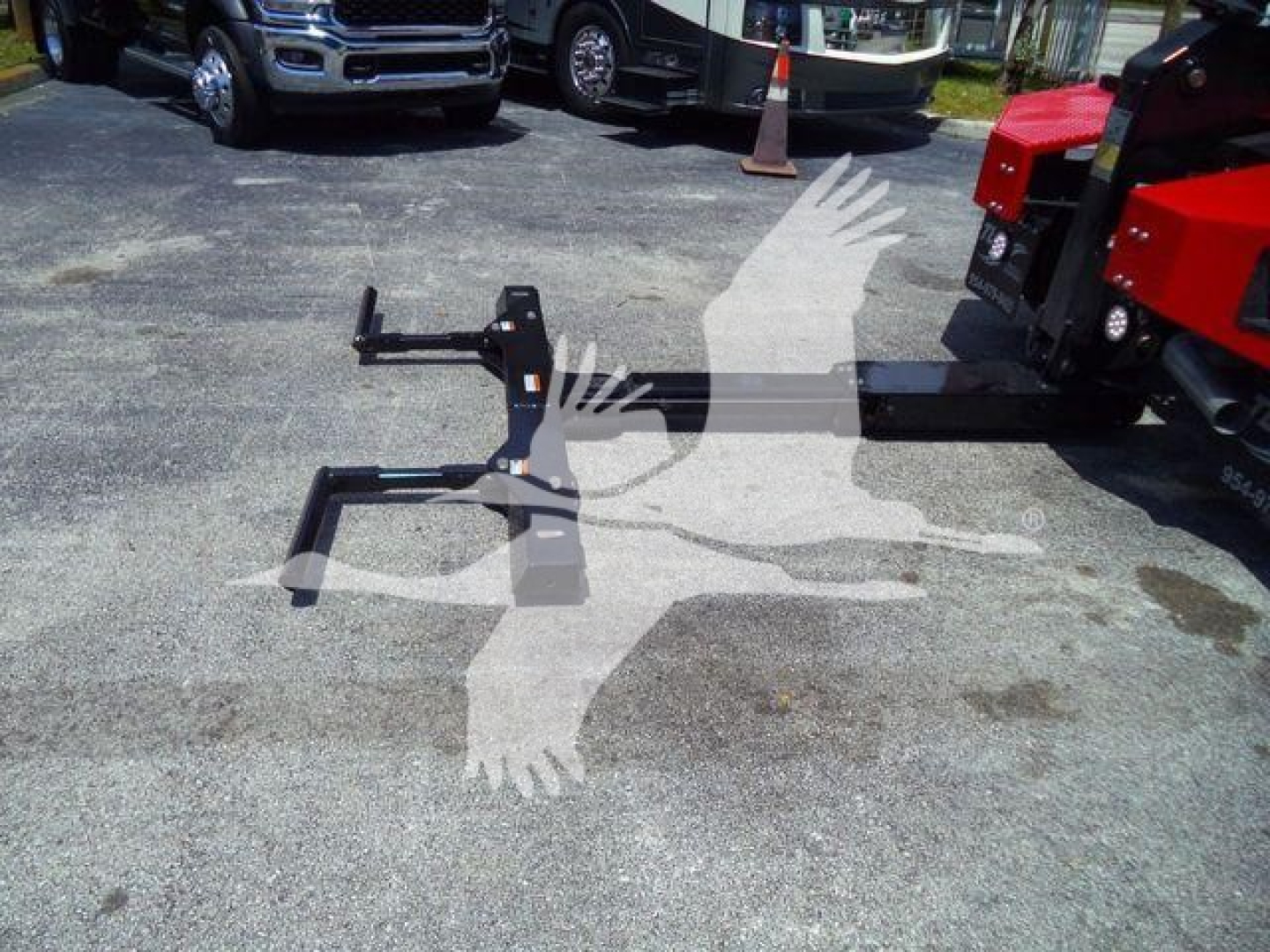 Truck equipment stand and hitch attachment on pavement with vehicles in background. No legible brand text visible.