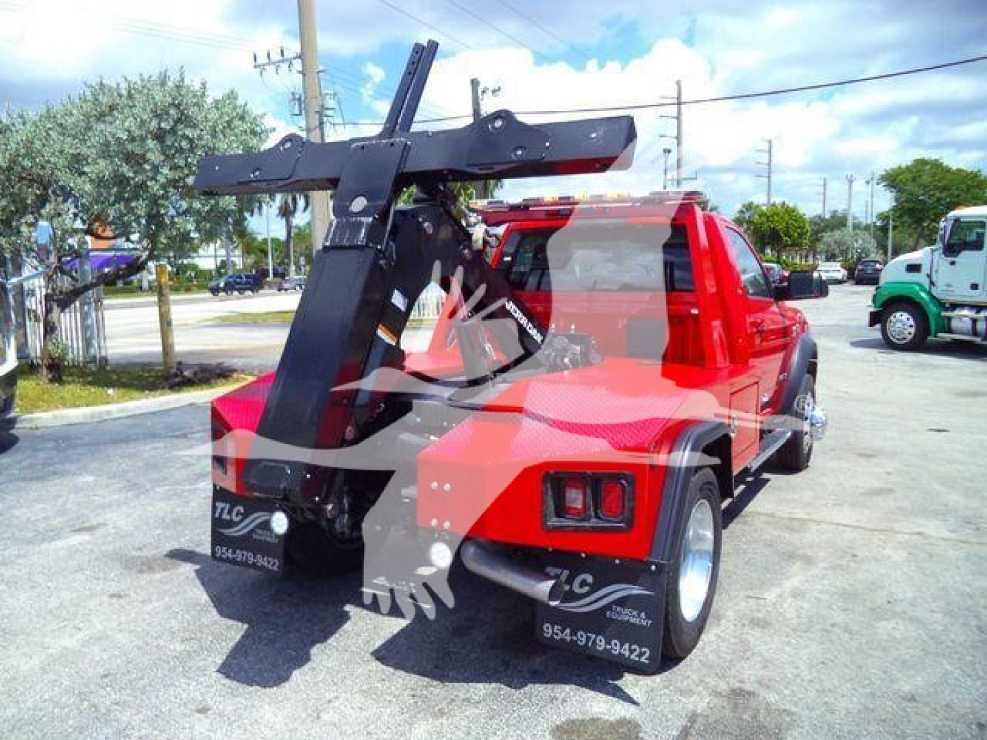 Ram 4500 tow truck rear view with a mounted winch/boom, red cab, black chassis, and tow hitch in a dealership lot.