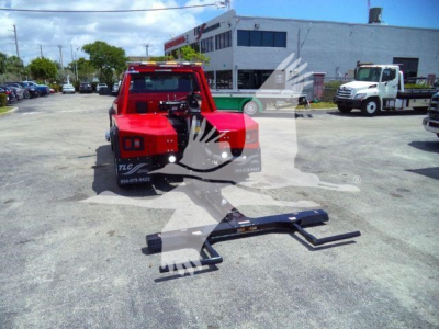 Ram 4500 SLT tow truck with winch kit resting on ground; red cab in background; front mounted winch frame and metal winch mounting brackets visible.