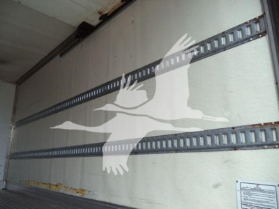 Truck trailer interior showing side rails and a reflective logo, with a white bird-like graphic on the wall.