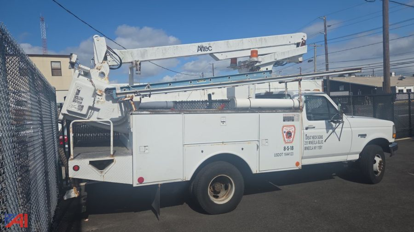Ford F-450 Super Duty bucket truck in-service side view with bucket boom raised, utility body compartments, and company decals on the door.