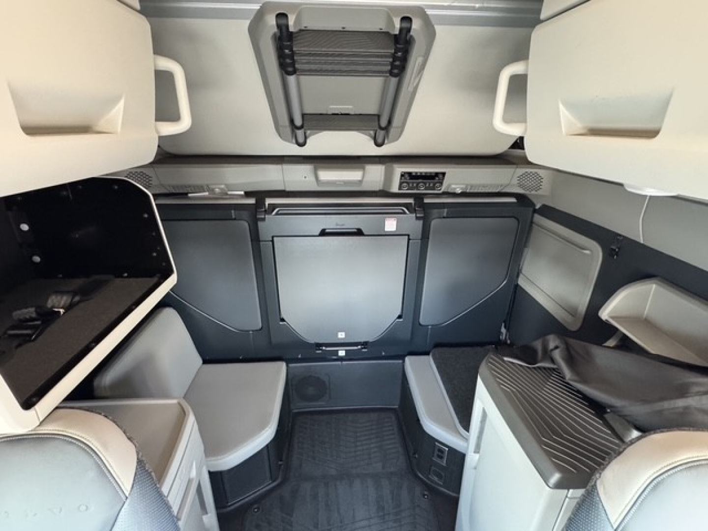Volvo VNL64T860 cab interior showing bunk area with overhead storage, side cabinets, and dashboard area faintly visible.