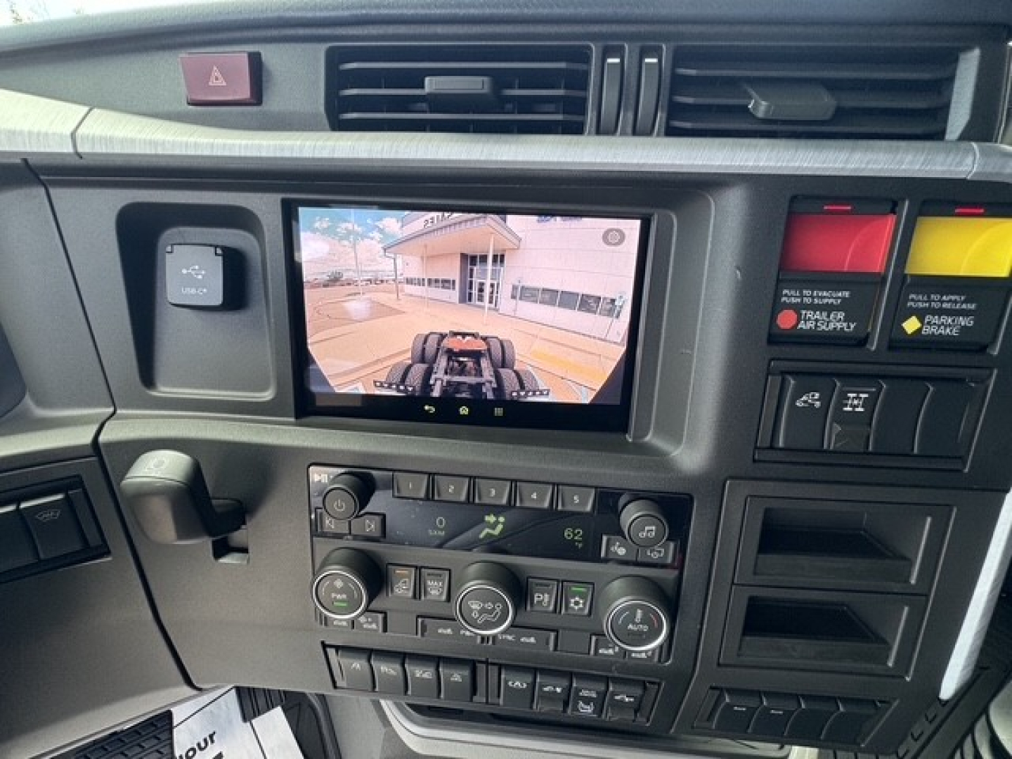 Volvo VNL64T860 truck dashboard with central touchscreen display showing rear camera view, climate controls, and various switches.