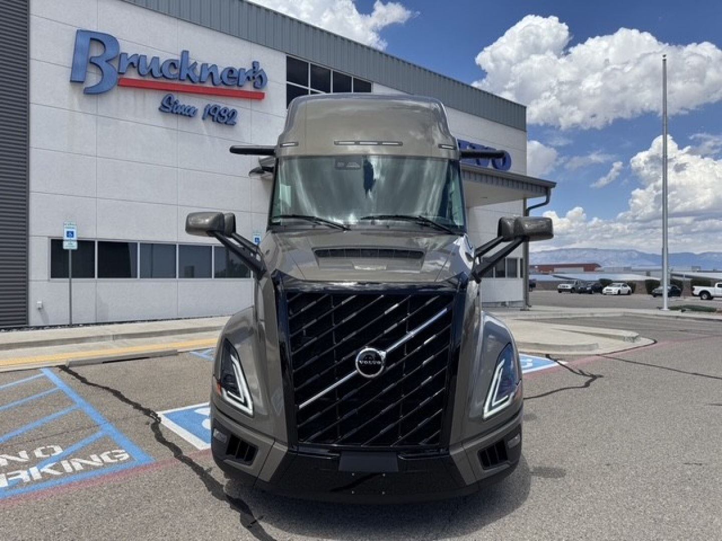 Volvo VNL64T860 front view with large black grille and Volvo emblem, daytime exterior at dealership lot.