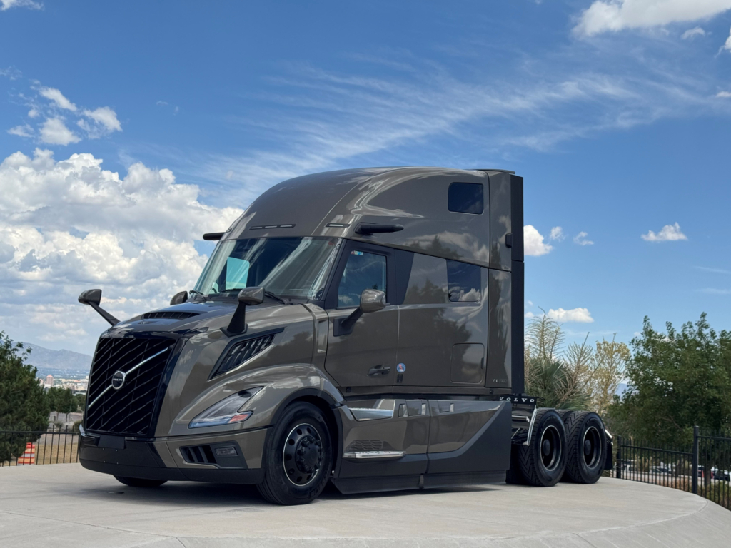 Volvo VNL64T860 cab with sleeper in view showing front grille, windshield, and side mirrors; diesel truck chassis and rear axles visible.