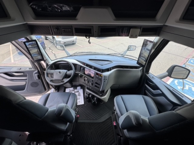 Interior of a Volvo VNL64T860 truck cabin showing the steering wheel, large dashboard with multiple screens, and two captain seats.