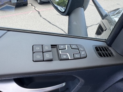 Interior close-up of Volvo VNL64T860 door panel with window/lock control switches visible.