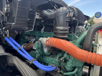 Volvo VNL64T860 engine bay showing orange engine coolant hose, blue hoses, and green engine block with intake, various components.