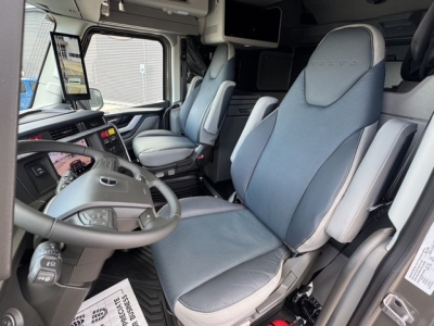 Volvo VNL64T860 truck cab interior showing driver seat and passenger seat with grey upholstery, steering wheel, dashboard, and overhead storage.