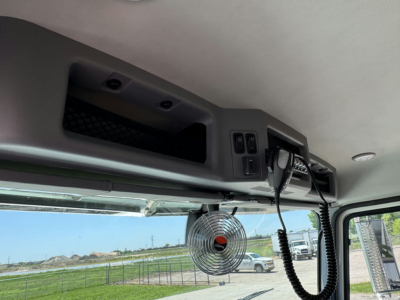 Mack GR64F cab interior showing overhead control panel, microphone, and a mounted small fan.