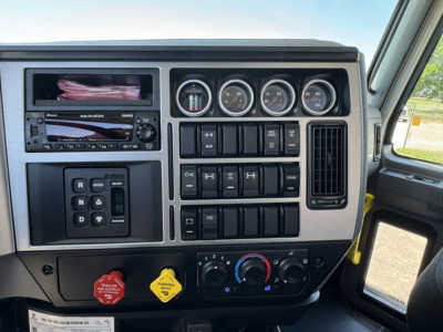 Dashboard of a 2026 Mack GR64F rollback truck showing multiple gauges, controls, and knobs; center console with switches, climate controls, and a circular gauge cluster.
