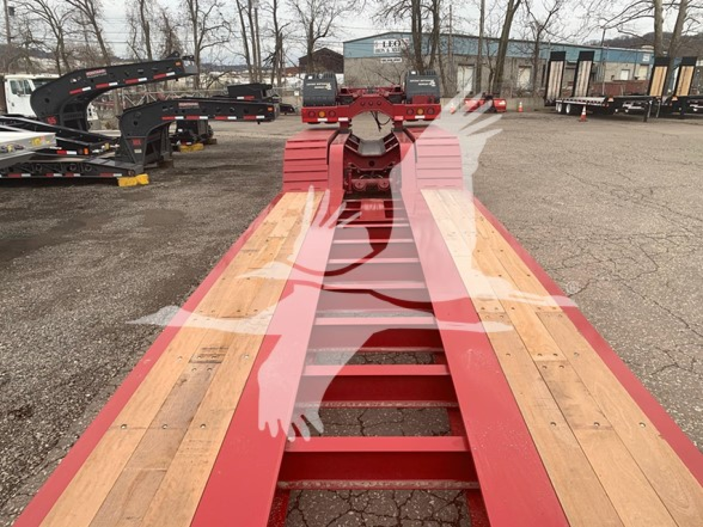 Fontaine lowboy trailer showing red main beams and wooden deck, front area with gooseneck hitch in view.