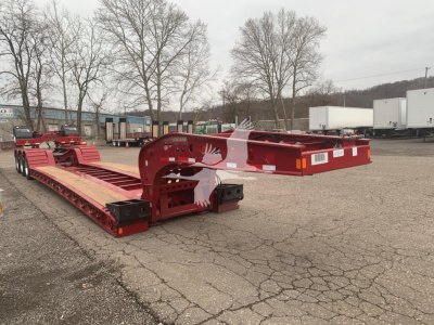 Lowboy trailer by Fontaine showing 55Lcc model in red with dual axles and long deck, VIN label and stock number sticker visible.